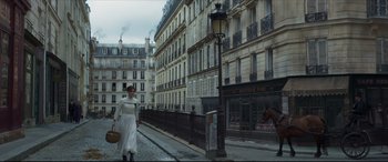 Movie still from “Colette” (2018), directed by Wash Westmoreland – A woman walking down the street in a white dress; Wide shot, Low angle