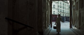 Movie still from “Colette” (2018), directed by Wash Westmoreland – An older woman walking down a street with a basket; Wide shot, Low angle