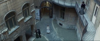 Movie still from “Colette” (2018), directed by Wash Westmoreland – A woman in a white dress standing in a courtyard; Extreme Wide shot, High angle