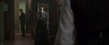 Movie still from “Colette” (2018), directed by Wash Westmoreland – A woman standing in front of a mirror holding a cane; Medium shot, Over the shoulder angle