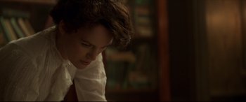 Movie still from “Colette” (2018), directed by Wash Westmoreland – A young man sitting in front of a book shelf; Close Up shot, Over the shoulder angle