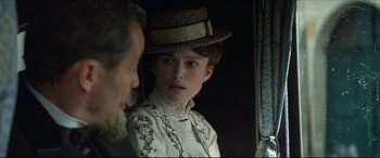 Movie still from “Colette” (2018), directed by Wash Westmoreland – A young woman wearing a straw hat looking at an older man; Close Up shot, Over the shoulder angle