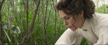Movie still from “Colette” (2018), directed by Wash Westmoreland – A woman in a white dress looking down at her face; Close Up shot, High angle