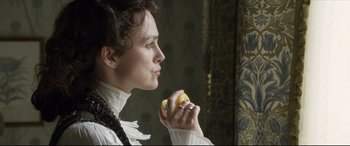 Movie still from “Colette” (2018), directed by Wash Westmoreland – A woman holding an apple in her hand; Close Up shot, Over the shoulder angle