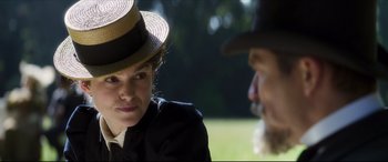 Movie still from “Colette” (2018), directed by Wash Westmoreland – A woman wearing a straw hat sitting next to a man wearing a cowboy hat; Close Up shot, Over the shoulder angle
