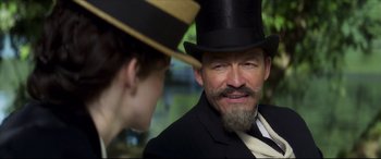 Movie still from “Colette” (2018), directed by Wash Westmoreland – A man in a suit and a hat looking at a woman in a hat; Close Up shot, Over the shoulder angle
