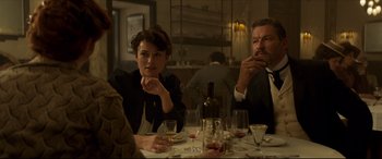 Movie still from “Colette” (2018), directed by Wash Westmoreland – A group of people sitting at a table with wine glasses; Medium shot, Over the shoulder angle