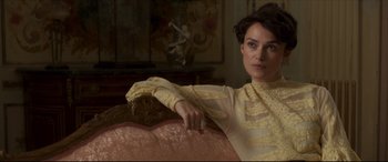 Movie still from “Colette” (2018), directed by Wash Westmoreland – A woman in a yellow dress sitting on top of a couch; Close Up shot, Over the shoulder angle