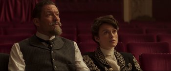 Movie still from “Colette” (2018), directed by Wash Westmoreland – A man and a woman sitting next to each other; Medium shot, Low angle