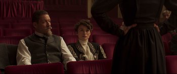 Movie still from “Colette” (2018), directed by Wash Westmoreland – A woman sitting in an audience wearing a black jacket; Medium shot, Over the shoulder angle