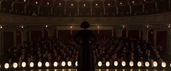 Movie still from “Colette” (2018), directed by Wash Westmoreland – A woman standing in front of an audience in a theater; Extreme Wide shot, High angle