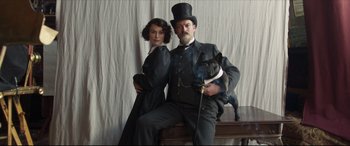 Movie still from “Colette” (2018), directed by Wash Westmoreland – A man and a woman posing for a picture with a dog; Medium shot, Low angle