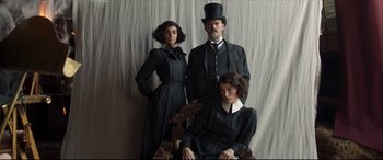 Movie still from “Colette” (2018), directed by Wash Westmoreland – A man and two women dressed up in black; Medium shot, Low angle
