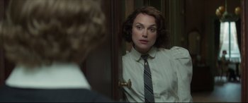 Movie still from “Colette” (2018), directed by Wash Westmoreland – A woman wearing a shirt and tie looking in a mirror; Close Up shot, Over the shoulder angle