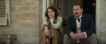 Movie still from “Colette” (2018), directed by Wash Westmoreland – A woman sitting next to an older man holding a glass of wine; Medium shot, Over the shoulder angle