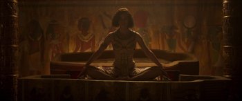 Movie still from “Colette” (2018), directed by Wash Westmoreland – A woman sitting on the ground in front of an egyptian mural; Wide shot, High angle