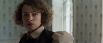 Movie still from “Colette” (2018), directed by Wash Westmoreland – A person with curly hair; Close Up shot, Over the shoulder angle