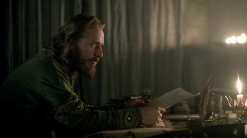 Movie still from “Vikings” (2013), created by Michael Hirst – A man sitting at a table writing on a piece of paper; Close Up shot, Over the shoulder angle