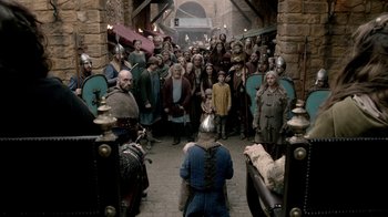 Movie still from “Vikings” (2013), created by Michael Hirst – A group of people standing in a hallway with helmets on; Wide shot, High angle
