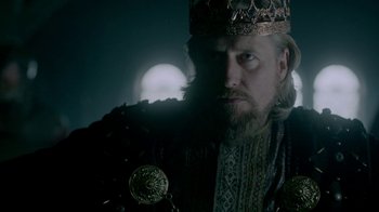 Movie still from “Vikings” (2013), created by Michael Hirst – A man with a beard wearing a crown; Close Up shot, Low angle