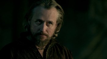 Movie still from “Vikings” (2013), created by Michael Hirst – A man with long hair and a beard wearing a brown shirt; Close Up shot, Over the shoulder angle