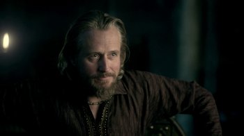 Movie still from “Vikings” (2013), created by Michael Hirst – A man with long hair and a beard wearing a brown shirt; Close Up shot, Over the shoulder angle