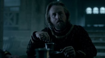 Movie still from “Vikings” (2013), created by Michael Hirst – A man sitting at a table with a cigarette in his mouth; Medium shot, Over the shoulder angle