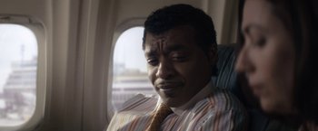 Movie still from “Come Sunday” (2018), directed by Joshua Marston – A person sitting on a plane; Close Up shot, Low angle