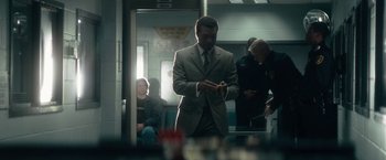 Movie still from “Come Sunday” (2018), directed by Joshua Marston – A man standing on a train looking at his cell phone; Medium shot, Over the shoulder angle