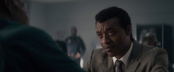 Movie still from “Come Sunday” (2018), directed by Joshua Marston – A person wearing a suit and tie; Close Up shot, Over the shoulder angle