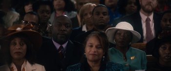 Movie still from “Come Sunday” (2018), directed by Joshua Marston – A group of people sitting in a room; Close Up shot, High angle