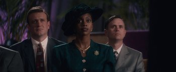 Movie still from “Come Sunday” (2018), directed by Joshua Marston – A woman in a green dress and a man in a suit and tie; Close Up shot, Over the shoulder angle