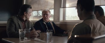 Movie still from “Come Sunday” (2018), directed by Joshua Marston – Two people sitting at a table with a laptop; Medium shot, Over the shoulder angle
