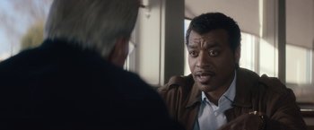Movie still from “Come Sunday” (2018), directed by Joshua Marston – A man talking to another man in front of a window; Close Up shot, Over the shoulder angle
