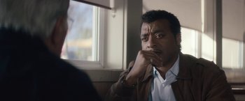 Movie still from “Come Sunday” (2018), directed by Joshua Marston – A person sitting in front of a window; Close Up shot, Over the shoulder angle