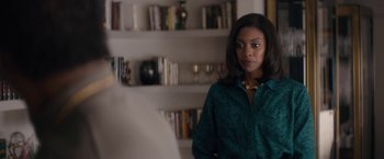 Movie still from “Come Sunday” (2018), directed by Joshua Marston – A woman standing in front of a book shelf; Medium shot, Over the shoulder angle