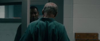 Movie still from “Come Sunday” (2018), directed by Joshua Marston – A man looking in the mirror in a jail cell; Close Up shot, Over the shoulder angle