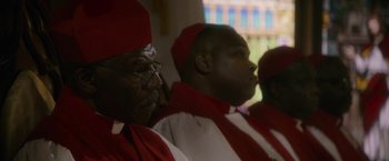 Movie still from “Come Sunday” (2018), directed by Joshua Marston – A group of men wearing red and white robes; Close Up shot, Low angle