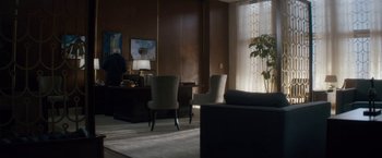 Movie still from “Come Sunday” (2018), directed by Joshua Marston – A living room filled with furniture next to a large window; Wide shot, Over the shoulder angle