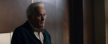 Movie still from “Come Sunday” (2018), directed by Joshua Marston – An older man wearing glasses looking out a window; Close Up shot, Over the shoulder angle