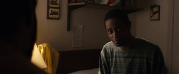 Movie still from “Come Sunday” (2018), directed by Joshua Marston – A young man sitting on a bed in a room; Close Up shot, Over the shoulder angle