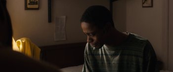 Movie still from “Come Sunday” (2018), directed by Joshua Marston – A man sitting on a bed looking down at a book; Close Up shot, High angle