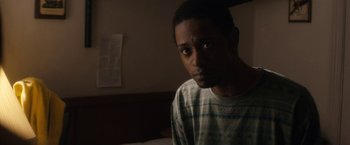 Movie still from “Come Sunday” (2018), directed by Joshua Marston – A man in a striped shirt is sitting on a bed; Close Up shot, Over the shoulder angle
