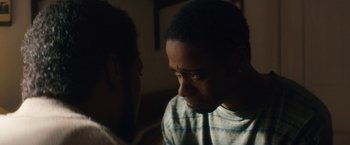 Movie still from “Come Sunday” (2018), directed by Joshua Marston – Two men are facing each other in the dark; Close Up shot, Over the shoulder angle