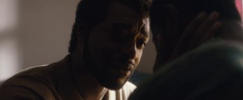 Movie still from “Come Sunday” (2018), directed by Joshua Marston – A man's face in a dark room; Close Up shot, Over the shoulder angle