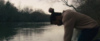 Movie still from “Come Sunday” (2018), directed by Joshua Marston – A man standing in front of a body of water; Medium shot, Low angle