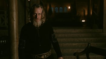 Movie still from “Vikings” (2013), created by Michael Hirst – A man with a long beard wearing a black shirt; Medium shot, Low angle