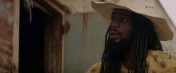 A man in a cowboy hat with long dreadlocks