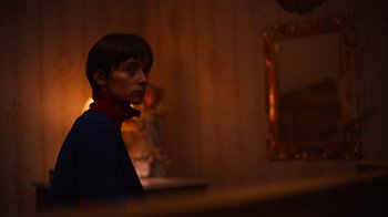Movie still from “Copenhagen Cowboy” (2022), created by Nicolas Winding Refn – A woman standing in front of a mirror in a dark room; Medium shot, Over the shoulder angle