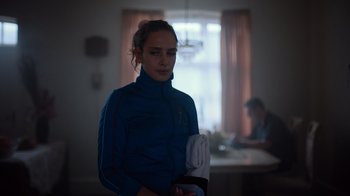 Movie still from “Copenhagen Cowboy” (2022), created by Nicolas Winding Refn – A woman in a blue jacket is holding a white glove; Close Up shot, Low angle